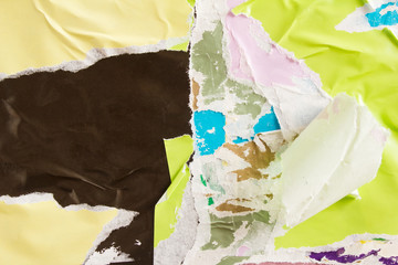 Beige yellow and black torn and crumpled paper posters on billboard with old shabby ripped and...