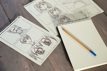 Artist drawing an anime comic book in a studio. Wooden desk, natural light
