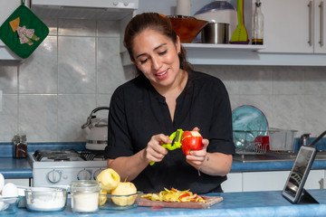 Cheerful real young woman peeling apples for a cake in the kitchen at home