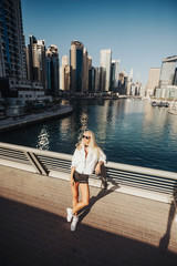 Fototapeta na wymiar Bright and clean overlooking lake view in an urban city emirates gulf country lifestyle. Russian lady photography in the city with tall building in surroundings.