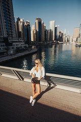 Fototapeta na wymiar Bright and clean overlooking lake view in an urban city emirates gulf country lifestyle. Russian lady photography in the city with tall building in surroundings tourist spot of Dubai.