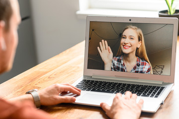 Back view of man making video call with his female friend or coworker while staying at home. Zoom,...