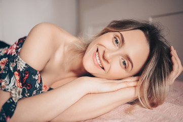 Obraz na płótnie Canvas Glamour fashion portrait of a beautiful smiling happy young woman lying on a bed