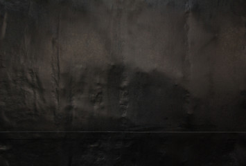 Black crumpled and peeling poster glued on street billboard. Black paper placard with rough wavy reflective surface texture background.