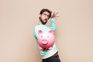 young cool man holding a piggy bank against clean wall