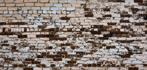 The brickwork of the old wall, uneven bricks and protruding mortar