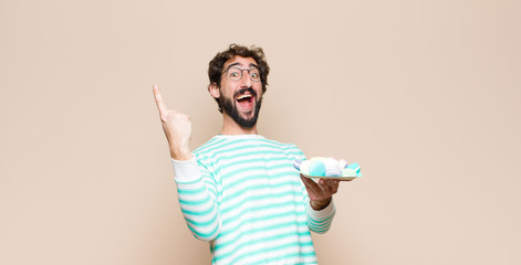 young man with macaroons against flat wall