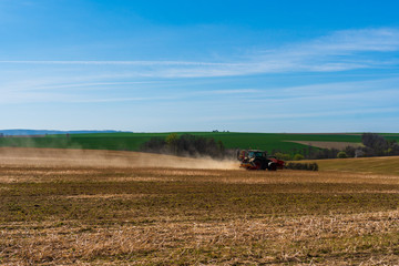 Naklejka premium Farmer in tractor sowing wheat field at spring , czech jeseniky 04.16.2020