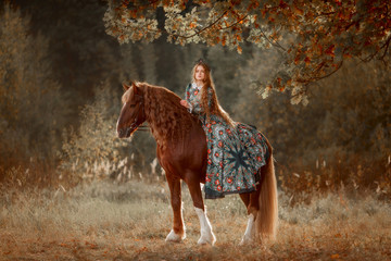 Beautiful long-haired blonde young woman in national russian style with red Vladimir draft horse in...