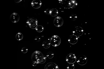 blurred transparent soap bubbles floating on the dark, bubbles abstract background, black background