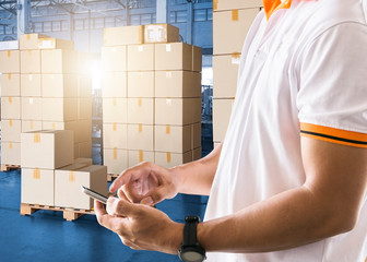 warehouse shipper hand holding smartphone with contacts to a customer, interior of warehouse shipping package boxes, business logistics shipment transport, cargo export