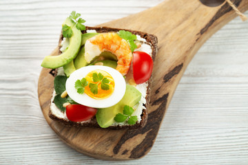 Toast with egg, shrimp, avocado, cheese, parsley and pine nuts