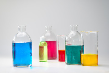 Glass bottles and flasks of different sizes with liquids of different colors on the background. Chemical lab.