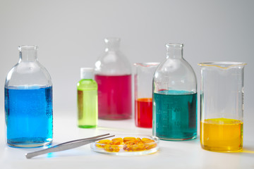 Glass bottles and flasks of different sizes with liquids of different colors on the background. Chemical lab.