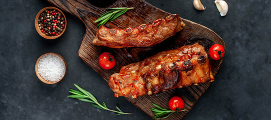 grilled pork ribs with spices and rosemary on a cutting board on a stone background
