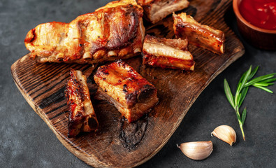 grilled pork ribs with spices and rosemary on a cutting board on a stone background