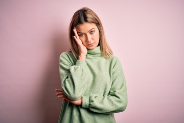 Young beautiful blonde woman wearing winter wool sweater over pink isolated background thinking looking tired and bored with depression problems with crossed arms.