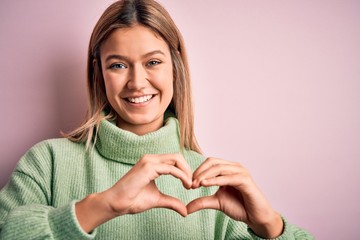 Young beautiful blonde woman wearing winter wool sweater over pink isolated background smiling in...