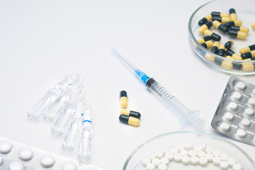 Various medical pills are on a white background. Syringe and vials with injection medication.