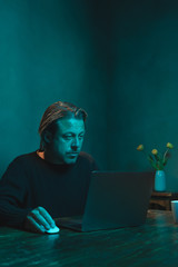 Man working at home behind laptop in the evening.
