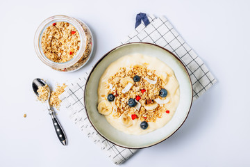Morning healthy breakfast bowl with yogurt, muesli, blueberry, banana, coconut on the white background.