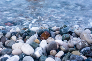 Sea waves breaking on pebbles. Pebbles through sea water.