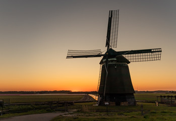 Holenderskie wiatraki nad kanałem wodnym, zachód słońca w Holandii Północnej