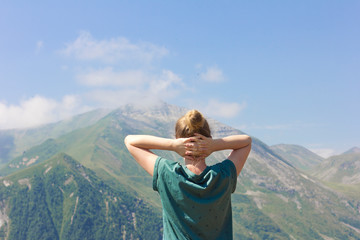 Young woman enjoys the clean air in the mountains. Tourist girl.