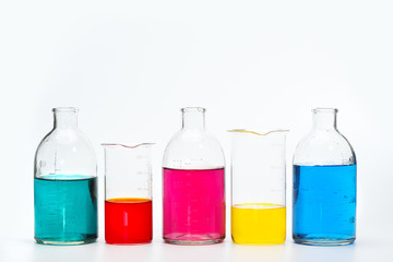 Glass bottles and flasks of different sizes with liquids of different colors on the background. Chemical lab.