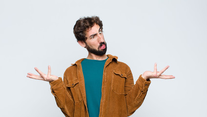 young handsome man shrugging with a dumb, crazy, confused, puzzled expression, feeling annoyed and...