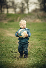 little boy plays ball outdoors