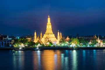 Night illuminated Temple of Dawn or Wat Arun and its reflection in Chao Phraya River at sunset. Bangkok, Thailand