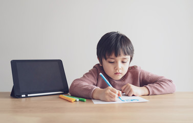 Kid self isolation using tablet for his homework,Child doing using digital tablet searching information on internet during covid 19 lock down,Home schooling,Social Distance,E-learning online education