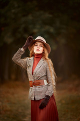 Beautiful long-haired blonde young woman in English style portrait in autumn forest