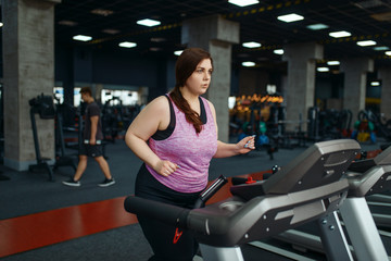 Overweight woman, exercise on treadmill in gym