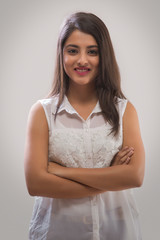 Portrait of a smiling teenage girl standing with her arms crossed
