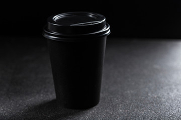 A silhouette of a paper refillable coffee Cup with a closed lid on a black background.
