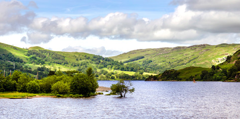 The bank of Ullswater in the Lake District showing the rambling hills and calm water. 