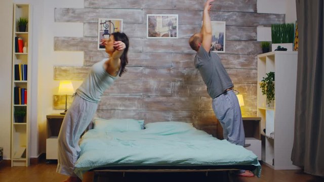 Caucasian young couple wearing pajamas falling back on bed before going to sleep.