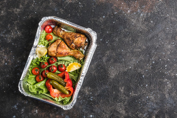 Safe delivery of ready-made food in foil. Chicken drumsticks with fresh vegetables and pickled...