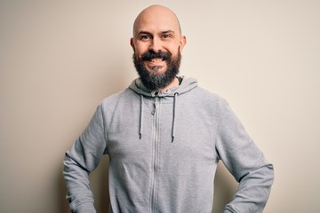 Handsome sporty bald man with beard wearing sweatshirt standing over pink background with a happy and cool smile on face. Lucky person.