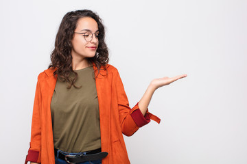 young pretty woman feeling happy and smiling casually, looking to an object or concept held on the...