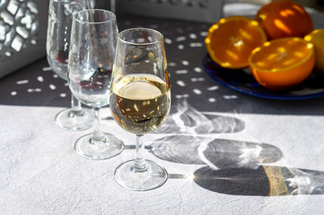 Glasses with cold fino sherry fortified wine and orange in sunlights, andalusian style interior on background
