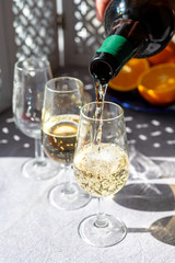 Pouring of cold fino sherry fortified wine in glass in sunlights, andalusian style interior on background