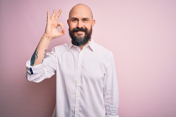 Handsome bald man with beard wearing elegant shirt over isolated pink background smiling positive doing ok sign with hand and fingers. Successful expression.