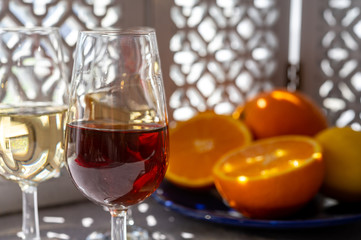 Glasses with cold dry fino and sweet cream sherry fortified wine and orange in sunlights, andalusian style interior on background