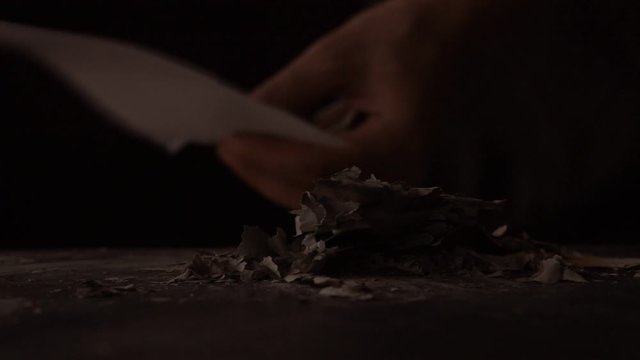 The man lights a paper with a match. Fire is a danger.