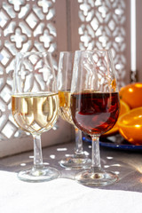 Glasses with cold dry fino and sweet cream sherry fortified wine and orange in sunlights, andalusian style interior on background