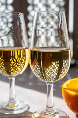 Glasses with cold dry fino and sweet cream sherry fortified wine and orange in sunlights, andalusian style interior on background