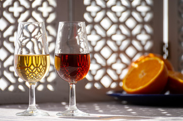 Glasses with cold dry fino and sweet cream sherry fortified wine in sunlights, andalusian style interior on background